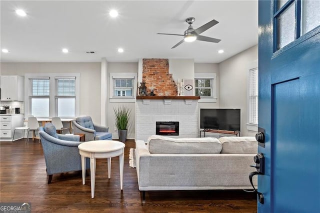 living area featuring dark wood-style floors, a fireplace, visible vents, and recessed lighting