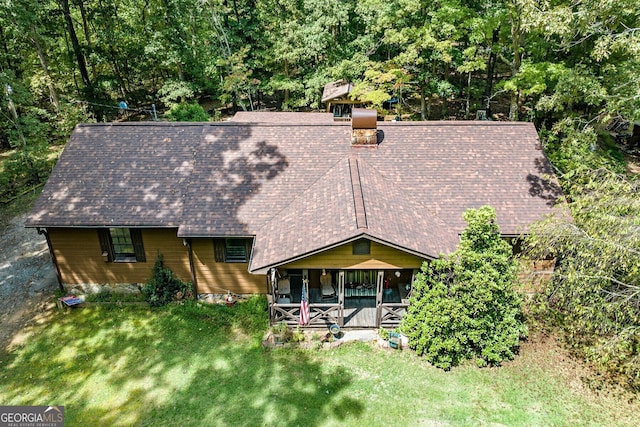 view of front of property with covered porch, a chimney, and a front yard