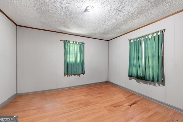 spare room with crown molding, a textured ceiling, and wood finished floors