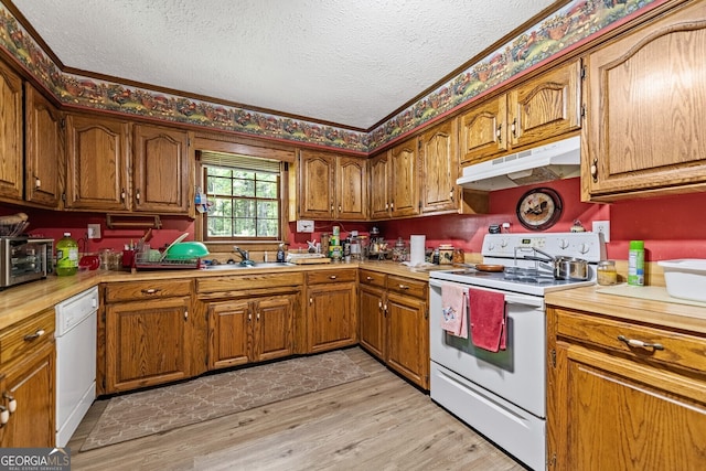 kitchen with brown cabinets, light wood finished floors, light countertops, white appliances, and under cabinet range hood