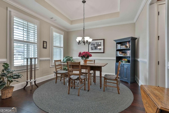 dining room with a tray ceiling, a notable chandelier, dark wood finished floors, and baseboards