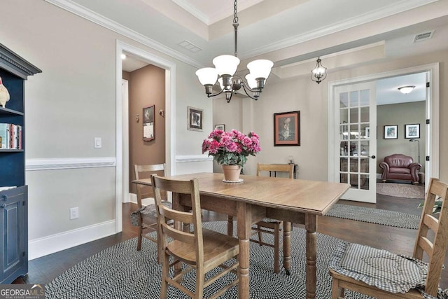 dining space with dark wood-type flooring, a chandelier, visible vents, and crown molding