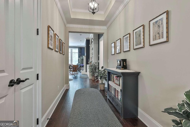 hall with baseboards, ornamental molding, dark wood finished floors, and a tray ceiling