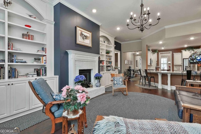 living area with crown molding, a brick fireplace, dark wood finished floors, and built in shelves