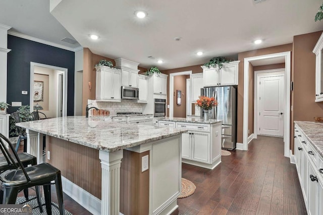 kitchen featuring dark wood-style floors, a center island, backsplash, appliances with stainless steel finishes, and white cabinets