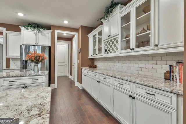 kitchen with light stone counters, dark wood-style flooring, glass insert cabinets, and white cabinetry