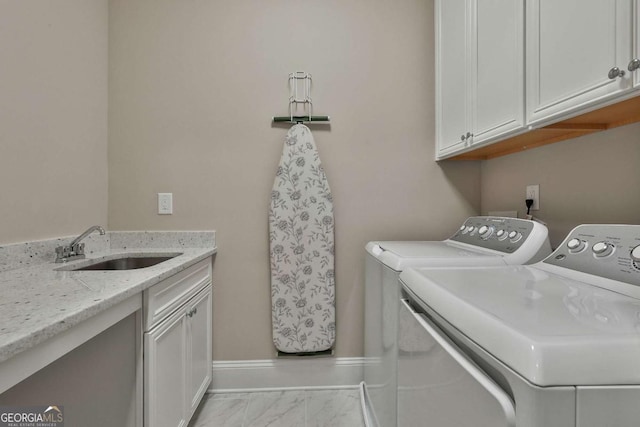 washroom featuring cabinet space, baseboards, marble finish floor, washing machine and dryer, and a sink