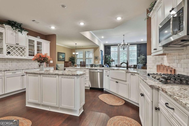 kitchen with appliances with stainless steel finishes, a chandelier, white cabinetry, and a peninsula