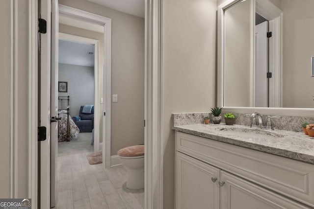 bathroom with baseboards, vanity, toilet, and wood finished floors