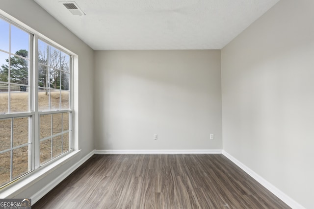 unfurnished room with visible vents, baseboards, and dark wood-style flooring