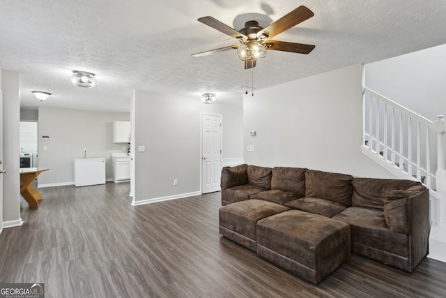 living area featuring baseboards, dark wood finished floors, ceiling fan, stairs, and a textured ceiling