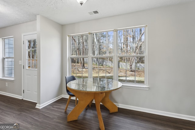 dining area with visible vents, a textured ceiling, baseboards, and wood finished floors