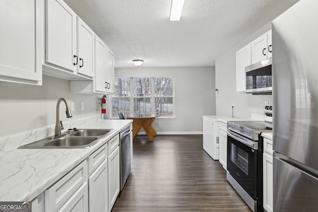 kitchen with a sink, dark wood finished floors, white cabinetry, appliances with stainless steel finishes, and light countertops