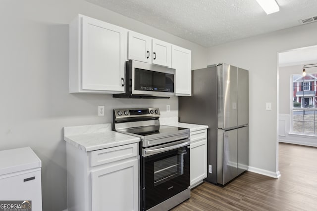 kitchen with visible vents, dark wood finished floors, light countertops, appliances with stainless steel finishes, and white cabinetry