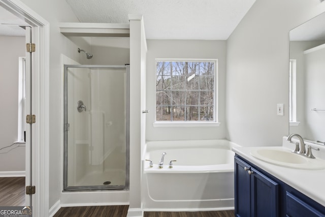 bathroom featuring vanity, a bath, wood finished floors, and a stall shower