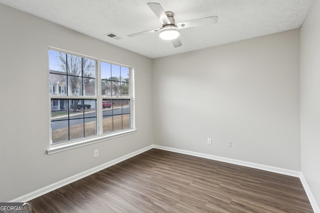 empty room with ceiling fan, visible vents, baseboards, and wood finished floors