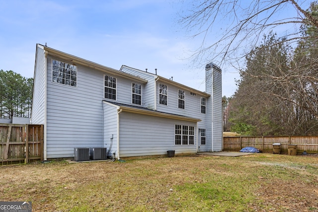 rear view of house with a patio, a chimney, a yard, and fence