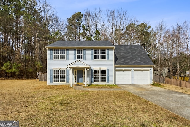 colonial house with an attached garage, concrete driveway, a front yard, and fence