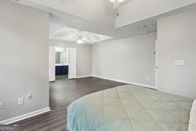 bedroom with dark wood-style floors, baseboards, ceiling fan, a textured ceiling, and a raised ceiling