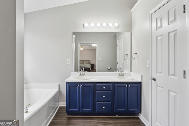 ensuite bathroom with a sink, a garden tub, wood finished floors, and ensuite bathroom