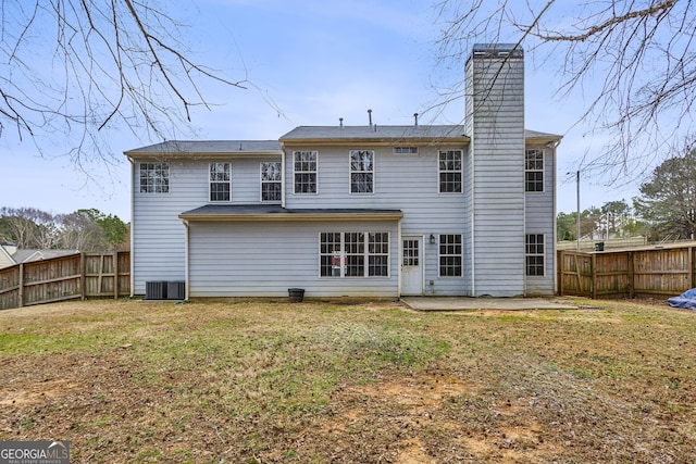 back of house featuring a patio, a lawn, a fenced backyard, and a chimney