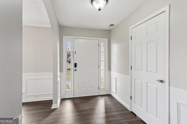 entryway featuring visible vents, a textured ceiling, wainscoting, and dark wood-style flooring