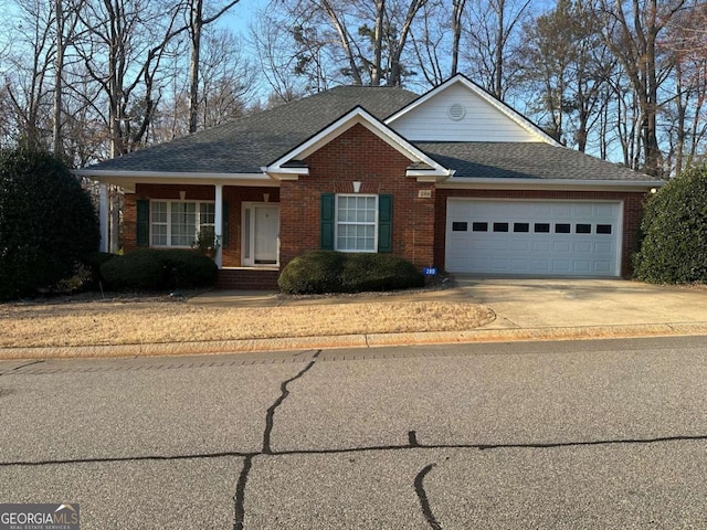 view of front of home with an attached garage, a shingled roof, concrete driveway, and brick siding