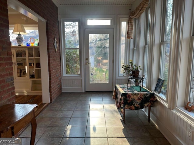 doorway to outside with brick wall and tile patterned floors