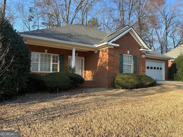 ranch-style home featuring brick siding, roof with shingles, an attached garage, and a front yard