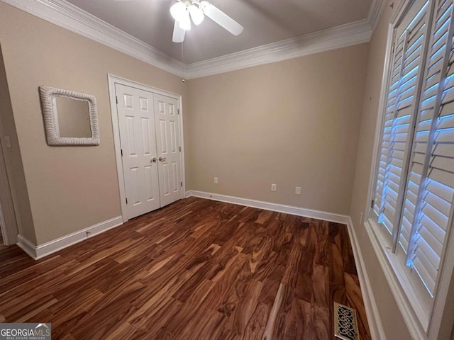 unfurnished bedroom featuring dark wood-style flooring, visible vents, crown molding, and baseboards