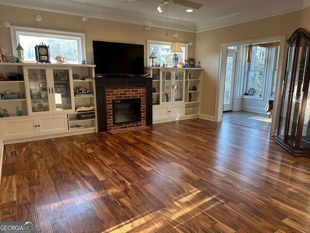 living area with a wealth of natural light, a brick fireplace, dark wood finished floors, and ceiling fan