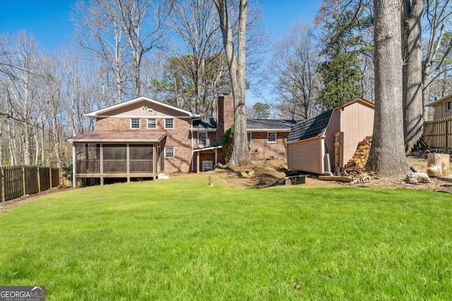 rear view of property with a lawn, a sunroom, a fenced backyard, a chimney, and an outdoor structure