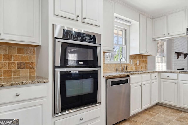 kitchen with white cabinets, tasteful backsplash, stainless steel appliances, and a sink