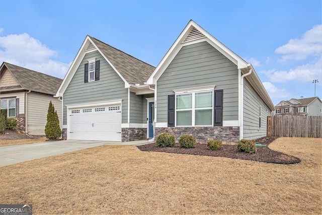 view of front of home featuring concrete driveway, stone siding, an attached garage, and fence