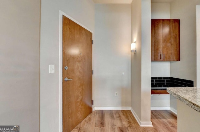 kitchen featuring brown cabinetry, light countertops, light wood-style flooring, and baseboards