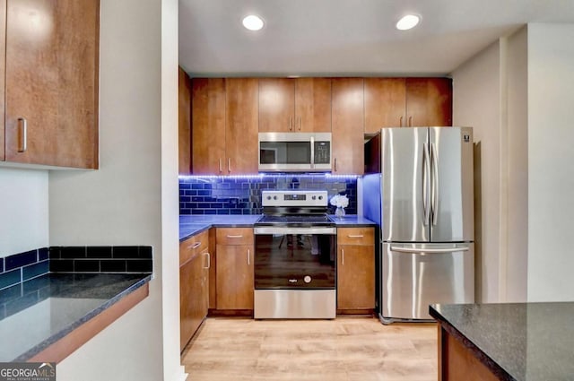 kitchen featuring brown cabinetry, stainless steel appliances, and backsplash