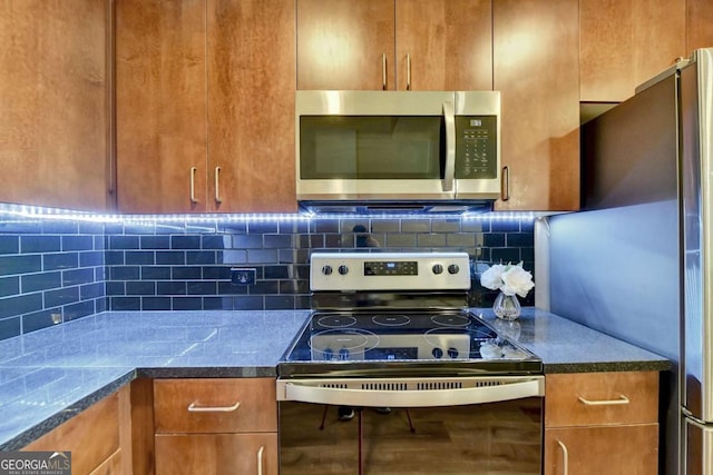 kitchen with dark countertops, brown cabinetry, tasteful backsplash, and stainless steel appliances