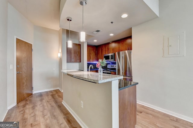 kitchen with baseboards, light wood-type flooring, light stone counters, appliances with stainless steel finishes, and a peninsula