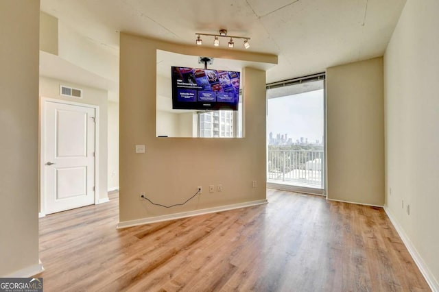 unfurnished dining area featuring a wall of windows, wood finished floors, visible vents, and baseboards