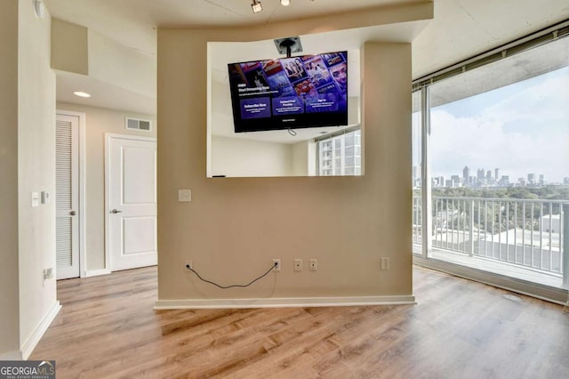 unfurnished living room featuring baseboards, visible vents, and wood finished floors