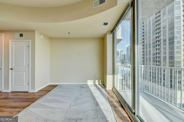 interior space featuring baseboards, a view of city, visible vents, and wood finished floors