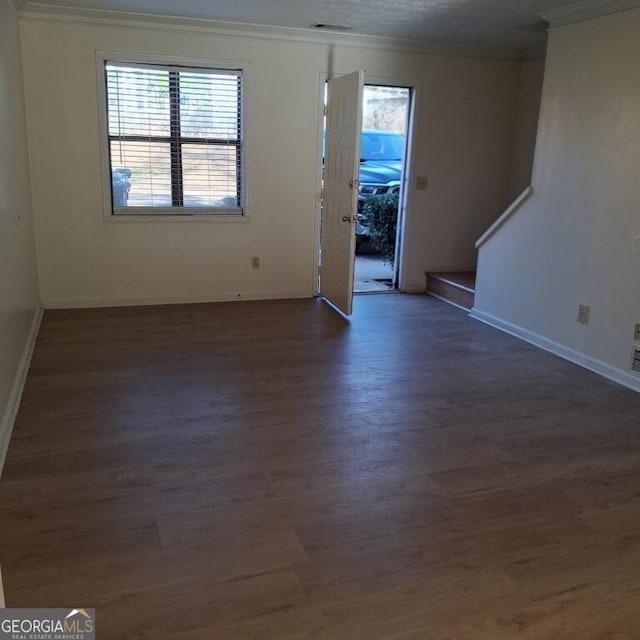 empty room featuring ornamental molding, visible vents, baseboards, and wood finished floors