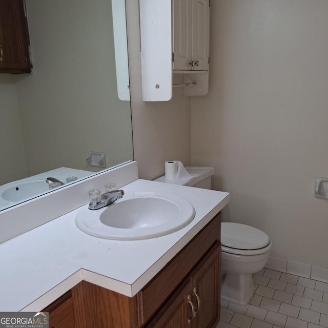 bathroom with toilet, tile patterned floors, baseboards, and vanity