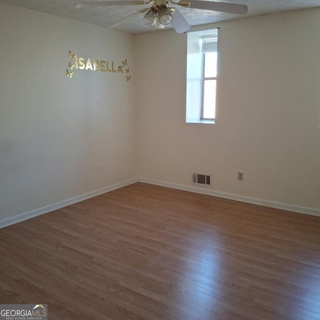 spare room with baseboards, wood finished floors, visible vents, and a ceiling fan