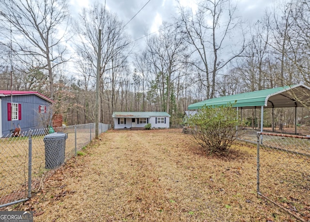 view of yard with a carport, fence, and an outbuilding