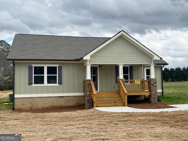 view of front facade with board and batten siding, covered porch, roof with shingles, and crawl space