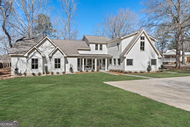 view of front of house with covered porch, a front lawn, and roof with shingles