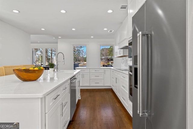 kitchen with a sink, visible vents, white cabinetry, high end fridge, and dark wood-style floors