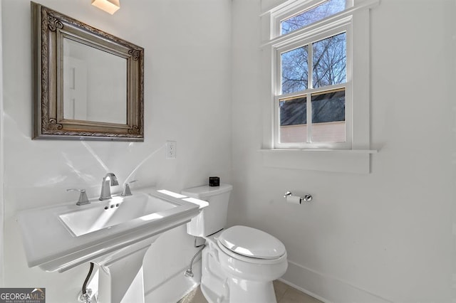 bathroom with toilet, baseboards, and a sink