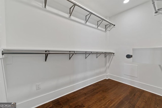 walk in closet with dark wood-style floors